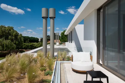 Terraza moderna con sofá curvo y vegetación exuberante — proyecto Casa AA, por Estudio Junor, en Pilar